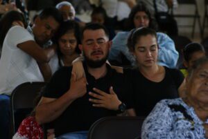 Group of men and women holding each other and praying