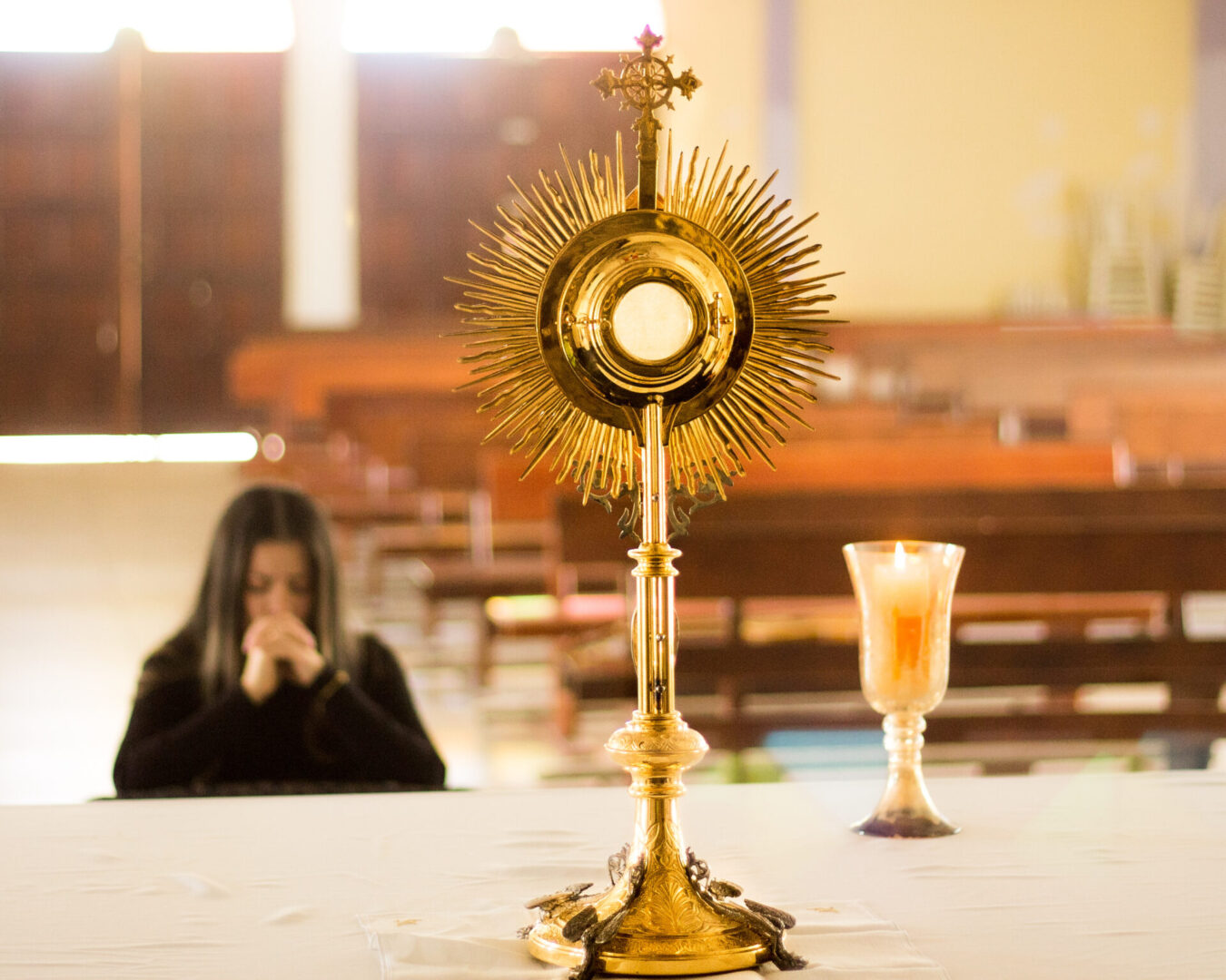 A woman praying in front of the eucharist monstrance