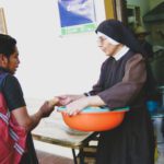 A catholic sister giving food to the person wearing a bag