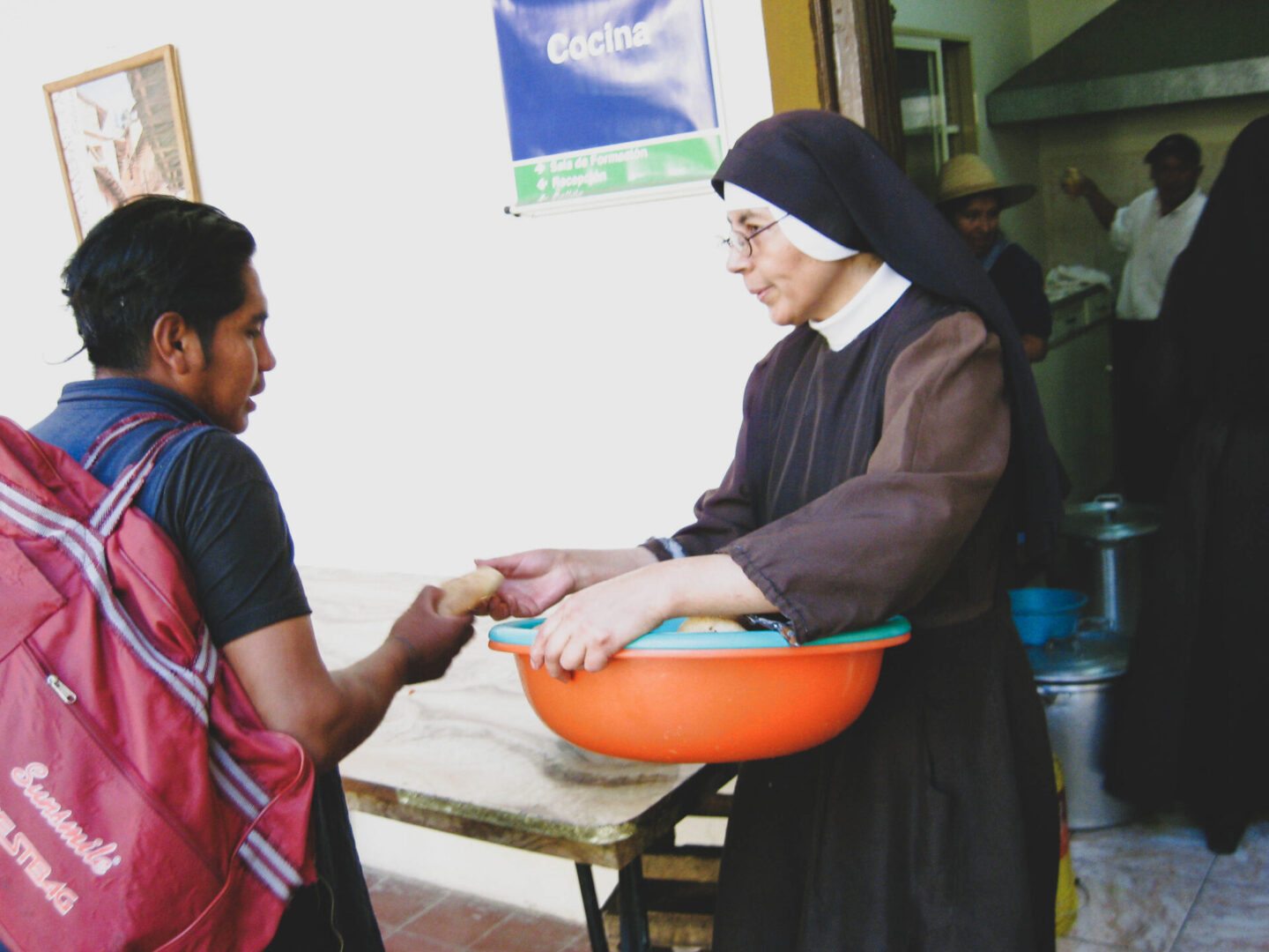 A catholic sister giving food to the person wearing a bag