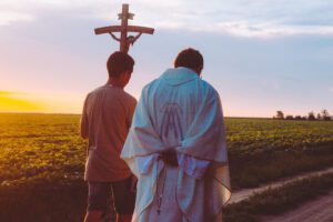 A priest and a person holding wooden Jesus lent cross