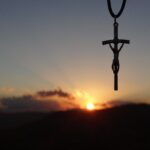 A jesus crucifix pendant with sunset in the background