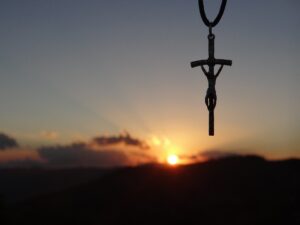 A jesus crucifix pendant with sunset in the background