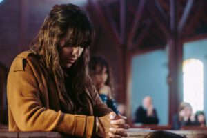 A woman praying inside the church holding her hands