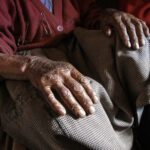 Close shot of an old woman hands on her knees