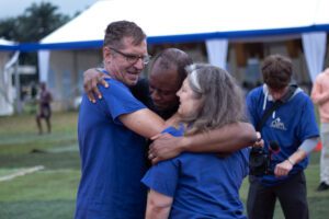 Paul Verderber, president of Gratia Vobis Ministries, his wife Mary Ann, and Fr. Maurice Emelu embrace in a joyful hug during the Jubilee of Hope event on July 10, 2025