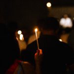 Person holding lit candle at vigil