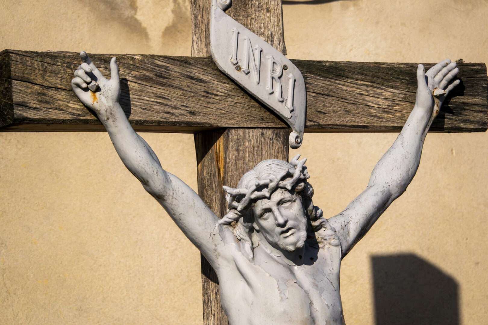 Outdoor crucifix detail with INRI plaque, warm sunlight highlighting Christ on the cross by Joan Sutter courtesy of Cathopic